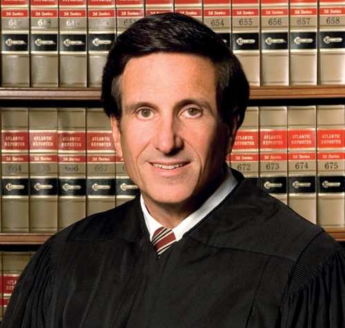 man in judge's robes standing in front of law books